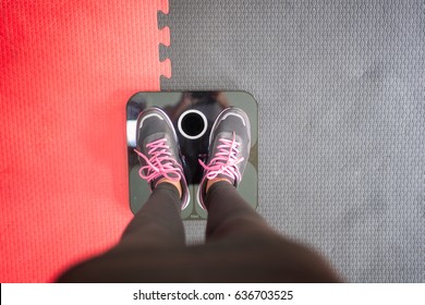 Woman standing on weigh scales at gym.Waist measurement by tape measure .Concept of healthy lifestyle.
