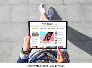 Woman standing outdoors and reading news on tablet computer