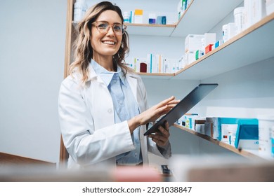 Woman standing in a pharmacy and using a tablet. Female pharmacist doing a stock take in a drug store. Portrait of a happy healthcare worker in a chemist.