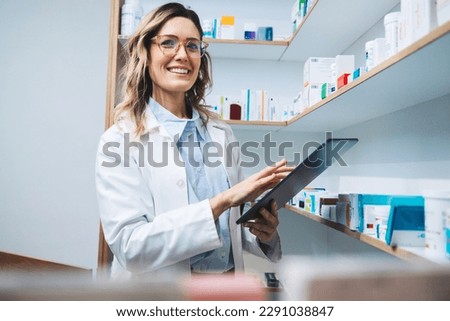 Woman standing in a pharmacy and using a tablet. Female pharmacist doing a stock take in a drug store. Portrait of a happy healthcare worker in a chemist.