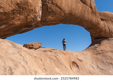 Woman standing in a rock arch in the Namibian Desert - Powered by Shutterstock