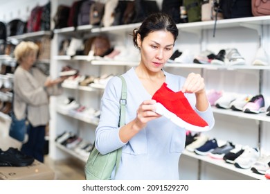 Woman Standing In Salesroom Of Shoeshop And Choosing New Running Shoes.