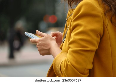 Woman standing with smartphone on a street on traffic lights background. Mobile communication in autumn city - Powered by Shutterstock