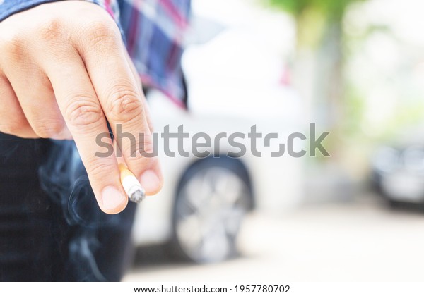 Woman standing\
smoking, focus on\
cigarettes