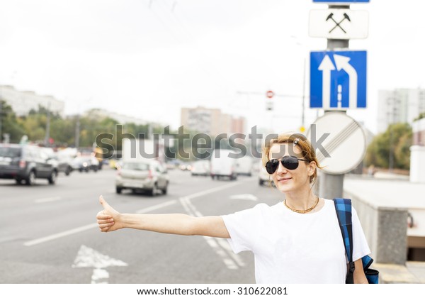 woman standing in\
the street, calling taxi 