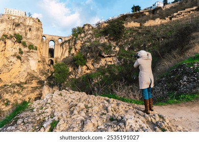 Woman standing while taking photos with a camera of the ancient city of Ronda in Spain - Powered by Shutterstock