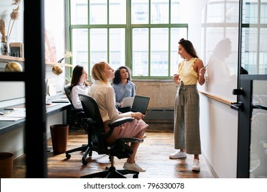Woman standing at whiteboard in a meeting with female team