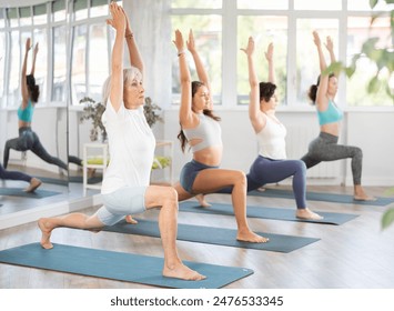 Woman standing yoga pose and making full body stretching workout with group in sports room - Powered by Shutterstock