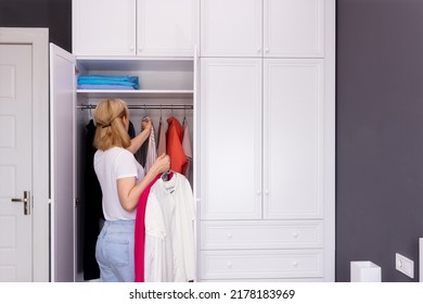 A Woman Stands In Front Of A Closet And Chooses Her Clothes For A Walk.