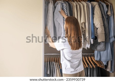 A woman stands in front of a closet and chooses her clothes for a walk.