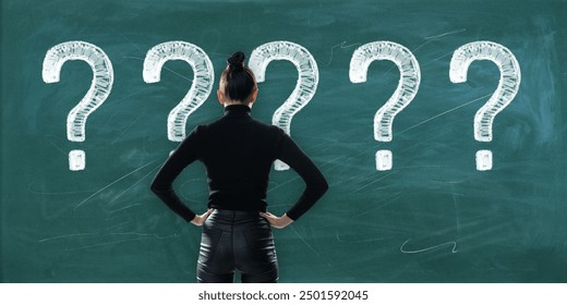 Woman stands with hands on hips in front of a chalkboard with multiple question marks drawn on it, symbolizing confusion or decision making. Concept of choice and problem solving - Powered by Shutterstock