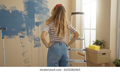 La mujer se para en el interior de una casa con una escalera y cajas de cartón, contemplando paredes pintadas de azul, encarnando la nueva renovación del hogar y el ambiente interior vibrante.
