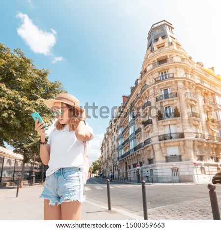 A woman stands near a typical Parisian residential corner house. Concept of apartments or hotels for tourists