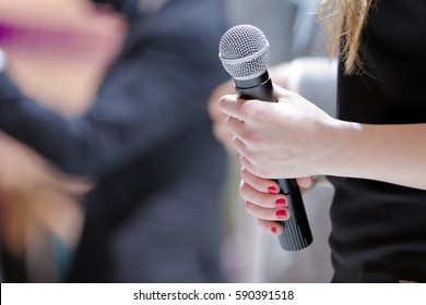 Woman Stands On Stage With Microphone
