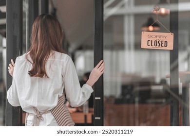 A woman stands outside a closed café, facing the door with a "CLOSED" sign visible, suggesting the establishment is no longer open for business. - Powered by Shutterstock