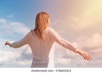 Woman Stands With Outstretched Arms Against The Backdrop Of A Solar Flare And Blue Sky