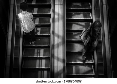 A Woman Stands Patiently On One Side Of An Escalator While Another Woman Runs Down The Other Side At A Train Station In Yokosuka, Japan.