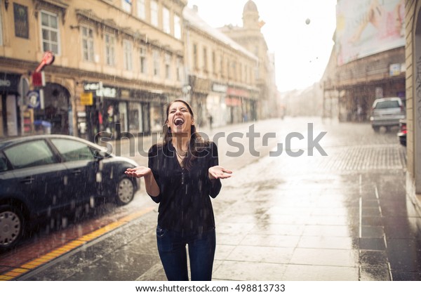 雨に打たれて楽しみながら立つ女性 通りに立ち 手を広げて雨が降る美しい若い濡れた女性のポートレート 軽快で楽しい人生のコンセプト の写真素材 今すぐ編集