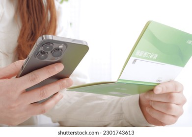A woman staring at the bankbook
						
						On the cover of the passbook, it is written as "savings account" in Japanese.