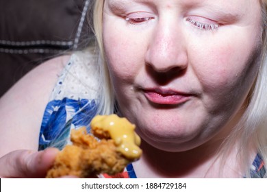 Woman Staring At A Partially Eaten Chicken Tender, Considering Whether She Wants To Continue Eating