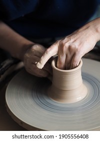Woman starts to create a ceramic cup on the pottery wheel. Working with clay on potter's wheel, closeup of hands, crafts and arts. Anonymous hands at work. Hobby and leisure with pleasure concept.