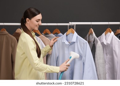 Woman steaming shirt on hanger in room - Shutterstock ID 2310728621