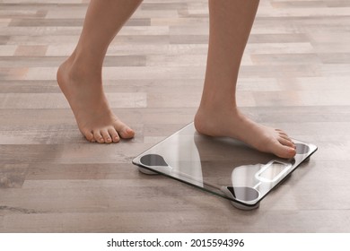 Woman stepping on floor scales indoors, closeup. Weight control - Powered by Shutterstock