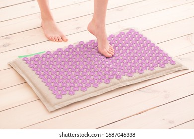 Woman Steps On A Pink Acupressure Mat. Home Self Massage, Acupuncture Concept.
