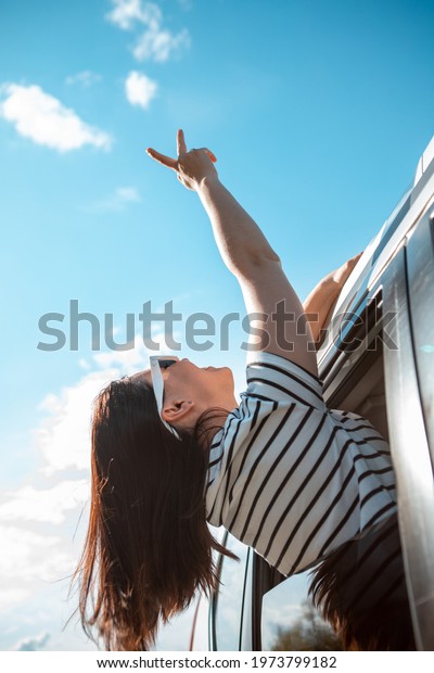 woman stick out of the car happy smiling face. sunny\
day. blue sky