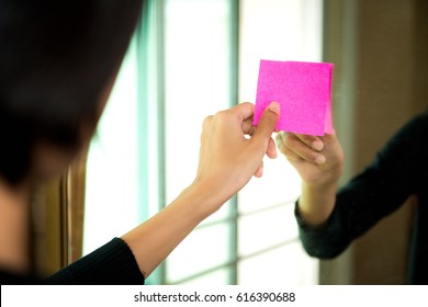 Woman sticking empty space , sticky note on mirror , Sticky note paper reminder schedule on mirror , Use post it notes to share idea on sticky note