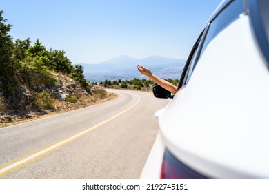 Woman Sticking Hand Out From The Open Window Driving A Car. Trip On The Serpentine Road In The Mountains. Summer Vacation. Freedom Concept. Copy Space