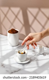 Woman Stir Coffee With Spoon. Coffee Cup, Hot Drink In A Mug. Beige And Marble Background With Window Shadow. Sunny, Sunshine. 