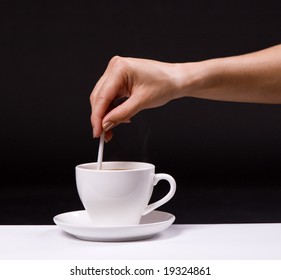 Woman Stir Sugar In Cup Of Coffee Over Black Background