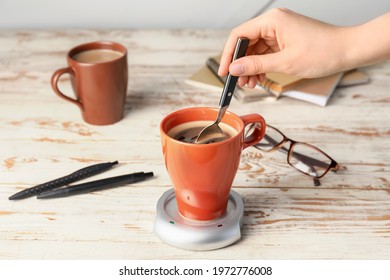 Woman stirring coffee in cup on table
