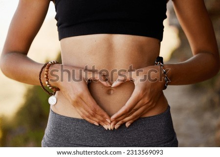 Woman, stomach and hand with heart in outdoor for exercise, diet, fitness and closeup. Female tummy, gut health and self love for wellness and training in the summer for healthy workout outside.