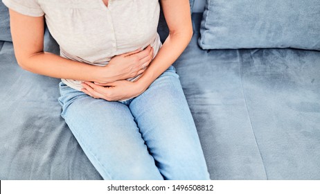 Woman With  Stomach Issues / Problems While Sitting On The Couch.