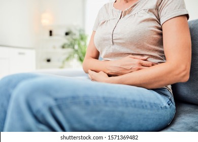 Woman With  Stomach Issues / Problems While Sitting On The Couch.