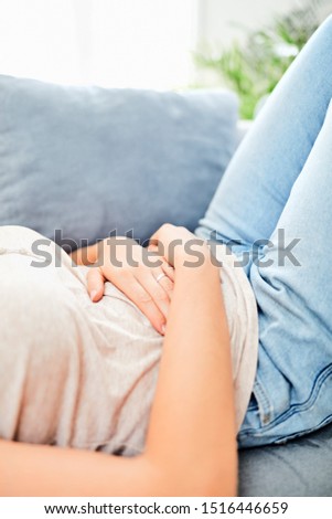 Woman with  stomach issues / problems while lying on the couch.