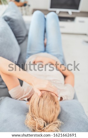 Woman with  stomach issues / problems while lying on the couch.