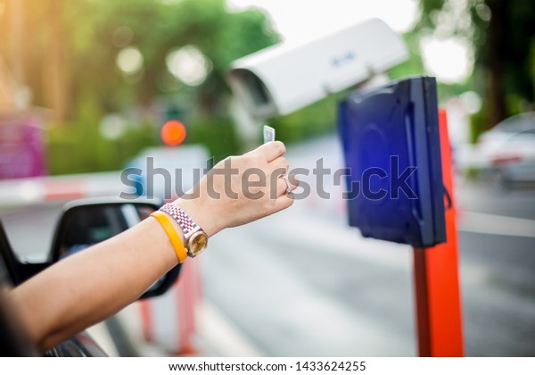 woman\
stop car and use key card to open the door for safety. driver hold\
card to scan at card reader station for open the car park door.\
security system for parking. the security\
concept.