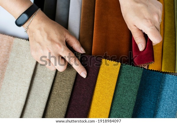 A woman in a store\
chooses a fabric for upholstered furniture in her new apartment,\
points to the color she liked in the catalog of special fabrics,\
close up. Top view