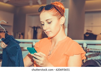 Woman  In Store Looking At Dress Tag Checking Matching Price Online On Her App Phone