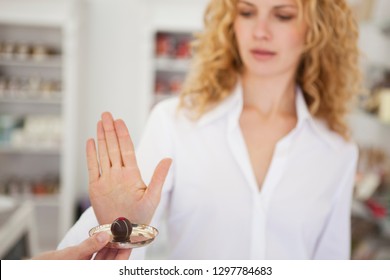 Woman In Store Refusing Chocolate Sample Offered To Her On A Plate