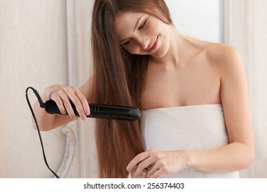 Woman Straightening Hair With Straightener