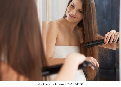 Woman Straightening Hair With Straightener