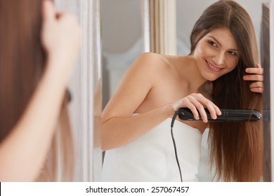 Woman Straightening Hair With Straightener