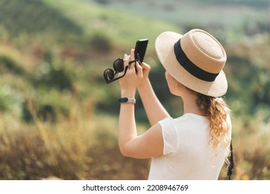 Woman In Straw Hat Making Photo Of Nature On Her Phone 