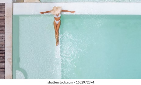 Woman In Straw Hat Relaxing In Clear Pool Water In Hot Sunny Day On Bali Villa. Summer Holiday Idyllic, Top View.