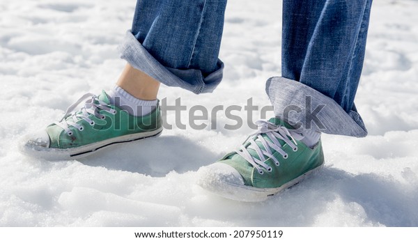 A woman with street shoes and pants rolled up having\
fun in the snow