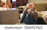 Woman, stress and moving on floor in house with boxes, headache and chaos with clothes in living room. Person, worry and anxiety with mess in lounge, apartment and relocation with property in Germany